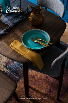 a wooden table topped with blue plates and goldware