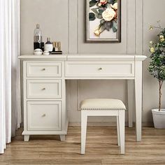 a white dressing table with stool and painting on the wall