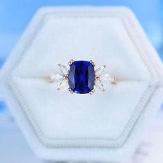 a blue sapphire and diamond ring sitting on top of a white box