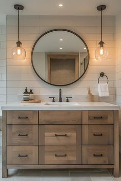 a bathroom vanity with two lights and a round mirror