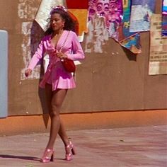 a woman in pink is walking down the street