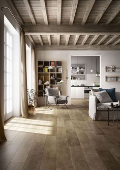 a living room filled with furniture and lots of wood flooring next to a window