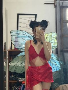 a woman in a red dress taking a selfie with her cell phone and butterfly wings behind her