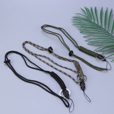 three lanyards with different types of leashes on white surface next to green plant