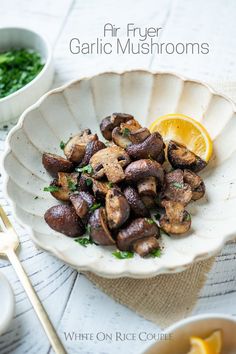 a white bowl filled with mushrooms and garnished with parsley on the side