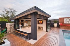 an outdoor living area with wooden decking and patio furniture next to a swimming pool