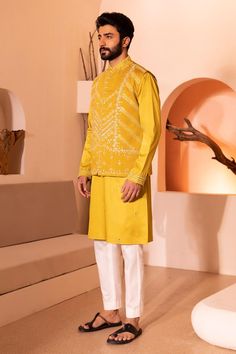 Yellow sleeveless waistcoat with all over hand embroidery in threads, sequins, beads and cutdana
Components: 1
Pattern: Hand Embroidery
Type Of Work: Beads, Sequins, Thread
Neckline: Round Neck
Sleeve Type: Sleevekess
Fabric: Padma Silk
Color: Yellow
Other Details: 
Note:
Kurta and pant worn by the model is not for sale
The outfits worn by the models at the back is not for sale
Occasion: Sangeet - Aza Fashions Festive Yellow Nehru Jacket With Resham Embroidery, Traditional Sleeveless Kurta With Mirror Work, Festive Outerwear With Handwork, Festive Sleeveless Kurta With Dabka Work, Festive Resham Embroidery Vest, Traditional Nehru Jacket With Handwork For Festivals, Designer Sleeveless Bandhgala With Resham Embroidery, Designer Sleeveless Bandhgala With Zari Work, Sleeveless Bandhgala With Resham Embroidery For Festive Occasions