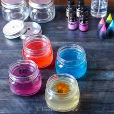 four jars filled with different colored dyes sitting on top of a table next to other bottles