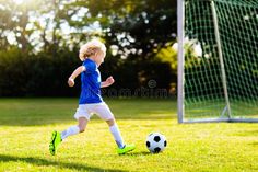 a little boy running towards a soccer ball on the field