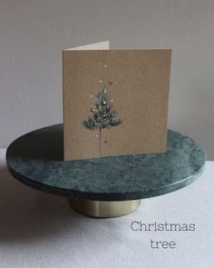 a card with a christmas tree on it sitting on a table next to a candle