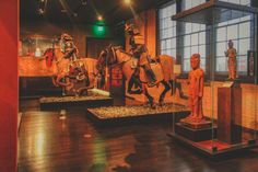 some statues are on display in a room with wood flooring and glass walls,