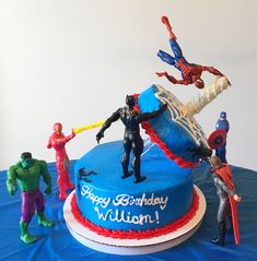 a birthday cake with figurines on it and an image of spider - man