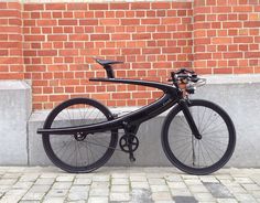 a black bicycle parked next to a brick wall