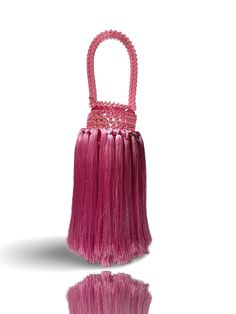 a pink handbag with long fringes on the handle and handles is shown in front of a white background