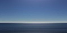 the sun is shining over the ocean on a clear day with blue sky and water