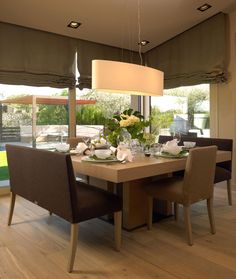 the dining room table is set with place settings and flowers on it, along with two lamps