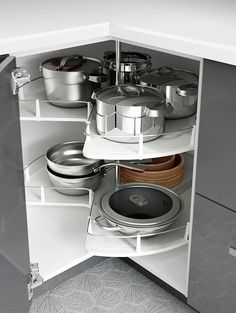 an open cabinet with pots and pans in it