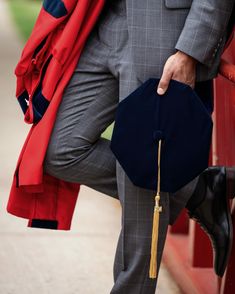 a man in a suit and tie holding a black hat with a tassel on it