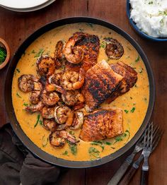 a pan filled with shrimp and grits on top of a wooden table