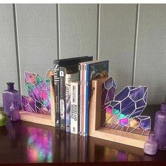 some books are sitting on a table with purple vases and other items in front of them