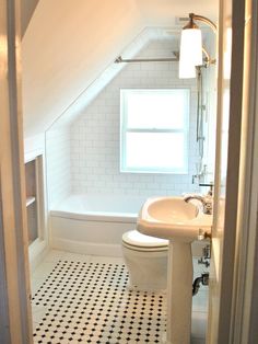 an attic bathroom with black and white floor tiles