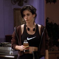 a woman holding a drink in her right hand and wearing a black shirt with the word nike on it