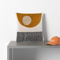 an orange hat is sitting on a table next to a pillow and a baseball cap