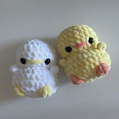 two crocheted stuffed animals sitting next to each other on a white table top