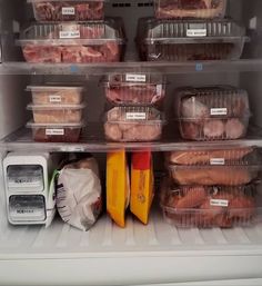 an open refrigerator filled with lots of meat and other food items in plastic bins