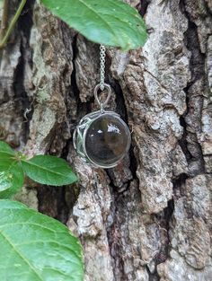 An extra large 20mm crystal clear quartz, tension set in a sterling silver, filigree, crescent moon shaped pendant.   The pendant is polished to a bright, shiny finish. Arrives with the pictured, 24 inch sterling silver rolo chain.  The 8th picture shows the filigree back of the mount. The chain shown is the chain that is included.   There has been no drilling or marring of the quartz whatsoever. The whole quartz sphere is what gives the piece its authenticity. Undrilled whole orbs are the hallm