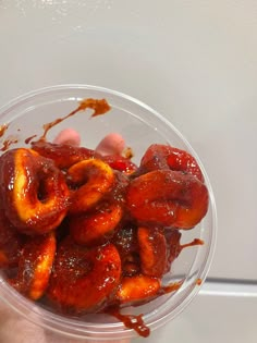 a person holding a plastic bowl filled with donuts