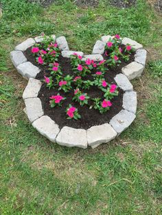 a heart shaped planter filled with flowers in the middle of some grass and dirt