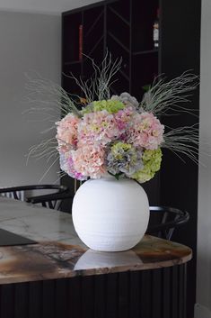 a white vase filled with flowers on top of a table