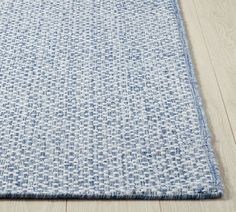 a blue and white rug on the floor with wood floors in the background, close up