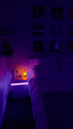 a bed in a dark room with purple light on the nightstand and side table next to it