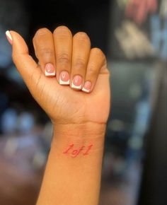 a woman's hand with pink and white nail polish on her left wrist, showing the number thirteen