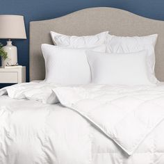 a bed with white sheets and pillows on it's headboard in a bedroom