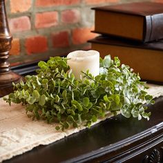 a candle and some green plants on a table