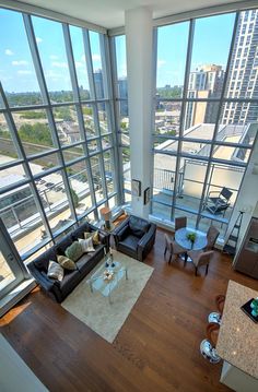 a living room filled with furniture and large windows overlooking a cityscape in the distance