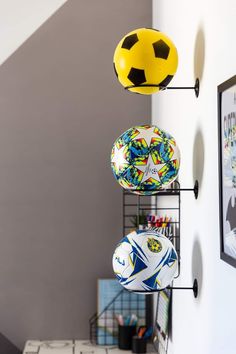 three soccer balls are hanging on the wall next to a shelf with other sports memorabilia