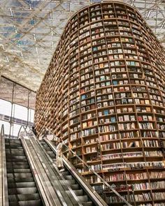 an escalator with bookshelves on the sides and people walking down it