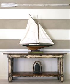 a boat is sitting on top of a table in front of a wall with striped walls