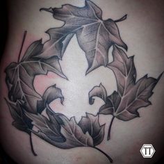 a tattoo design with leaves on the side of a woman's stomach, in black and white