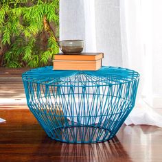 a blue table with books on top of it next to a planter and window