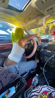 a woman with yellow hair sitting in the driver's seat of a car