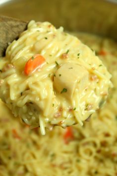 a wooden spoon full of macaroni and cheese with carrots on it,