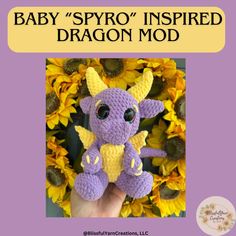 a purple crocheted dragon sitting on top of sunflowers with the caption baby spyo inspired dragon mod