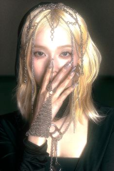 a woman with chains on her head covering her mouth and hands in front of her face