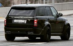 a black land rover is driving down the street