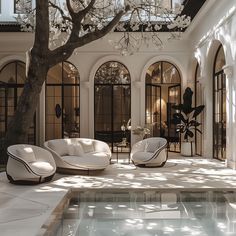 an outdoor living room with white furniture and large tree in the center, surrounded by arched windows